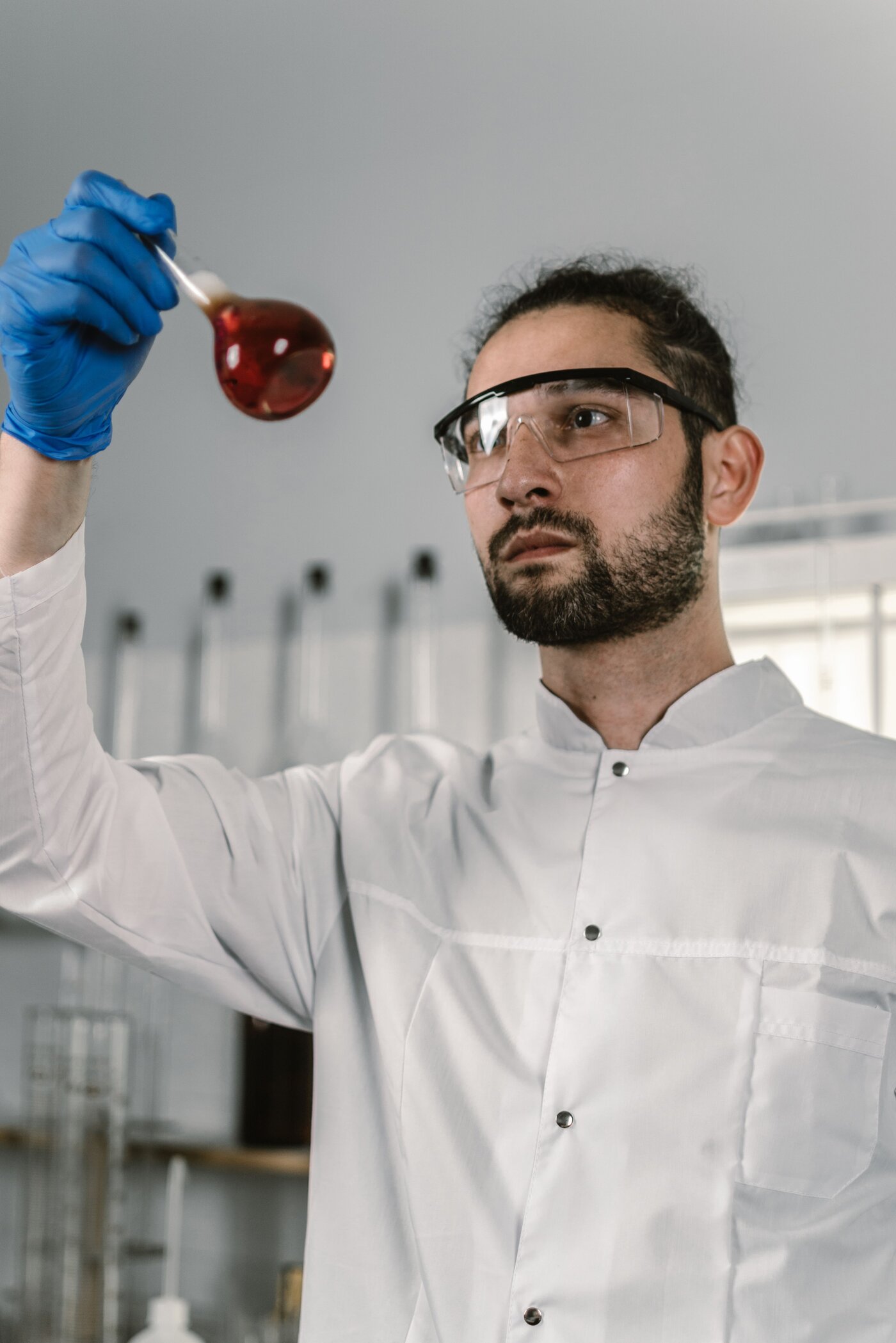 Process metallurgist inspecting chemical dissolution solution in laboratory flask